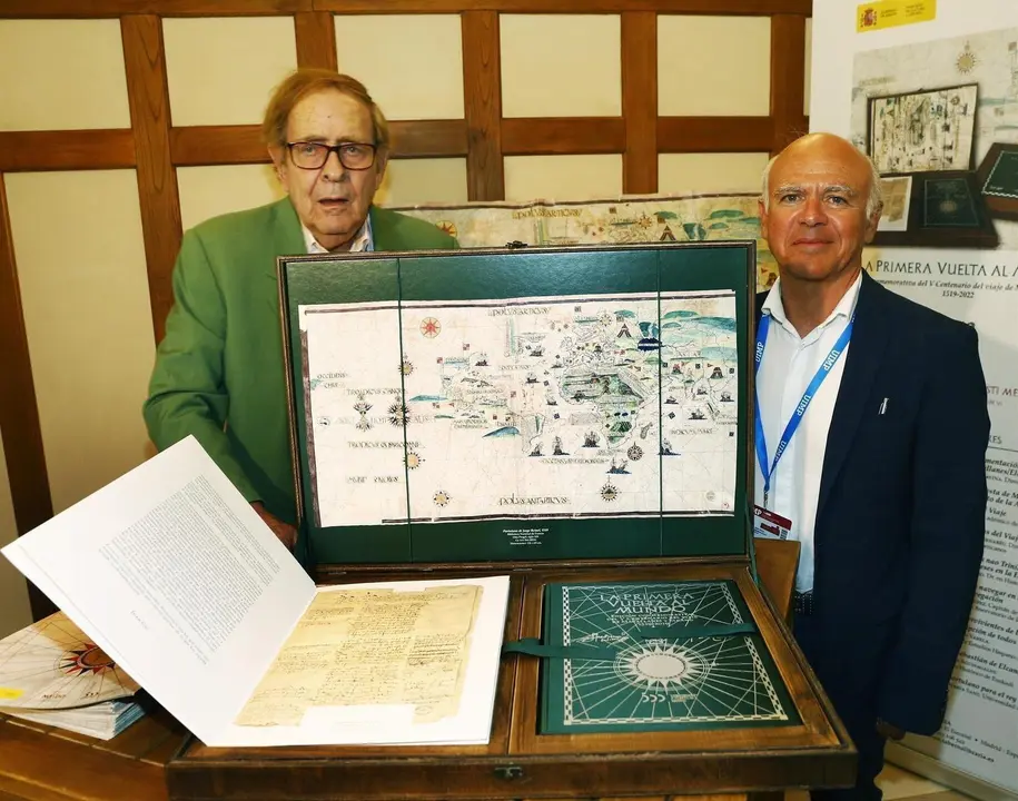 Jos&eacute; Mar&iacute;a Sanz Hermida y Ram&oacute;n Tamames con una copia de las ilustraciones de 'La Primera Vuelta la Mundo'
