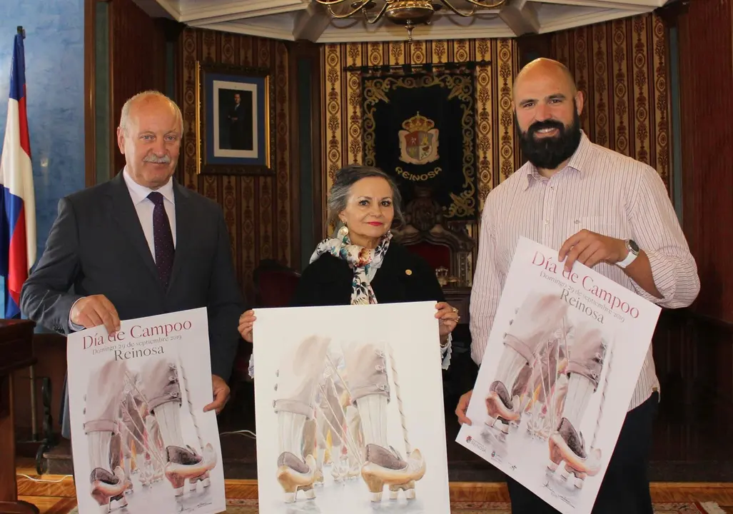 El alcalde de Reinosa, Jos&eacute; Miguel Barrio, Alicia Ca&ntilde;as y el concejal de Festejos, Daniel Santos, junto al cartel del Dia de Campoo.