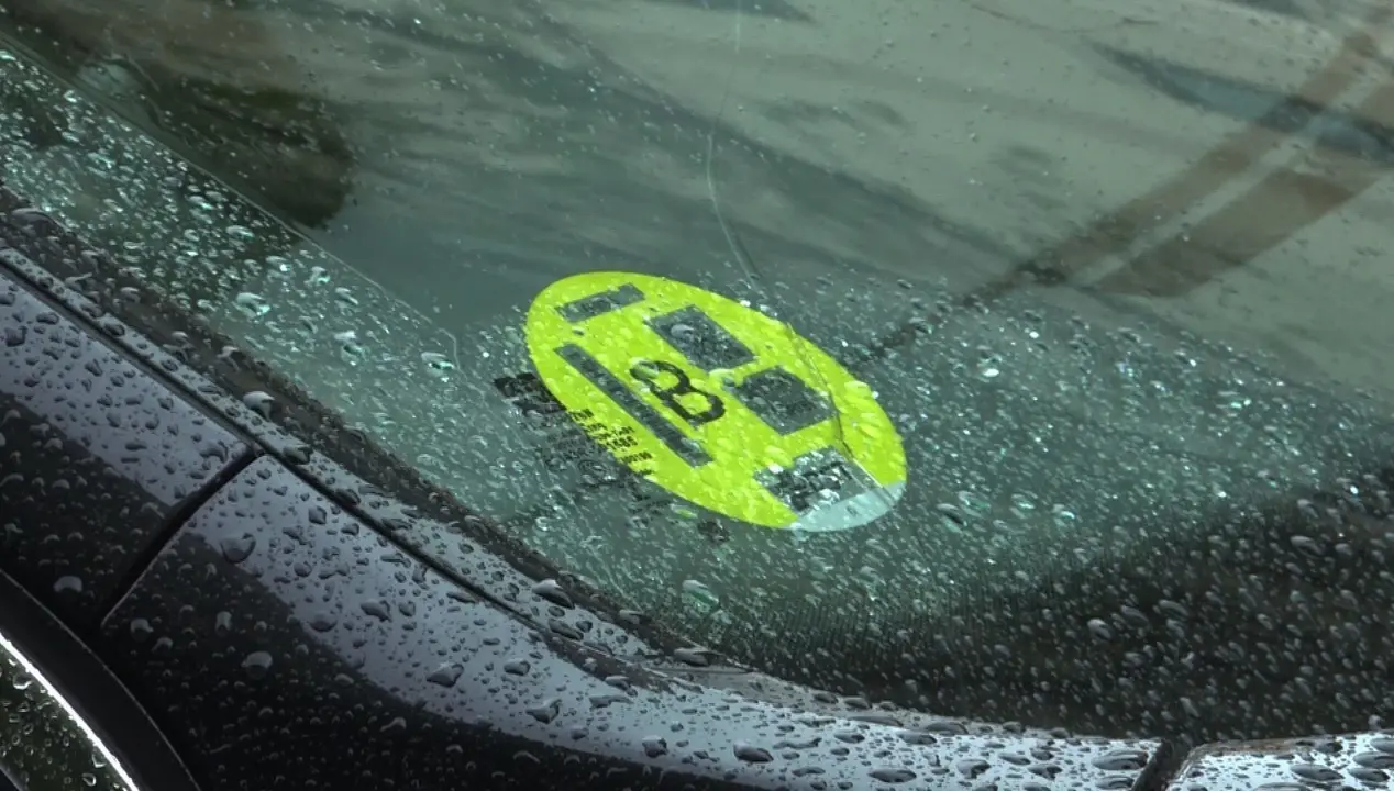 Un coche con un distintivo ambiental de la Direcci&oacute;n General de Tr&aacute;fico (DGT) de  tipo B, pegado en la luna.  