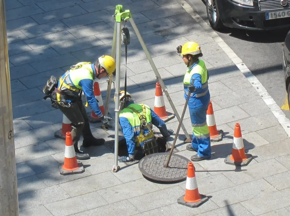 Seguridad en el trabajo, seguridad laboral, obreros con casco y chaleco reflectante, obra se&ntilde;alizada con conos, alcantarillado