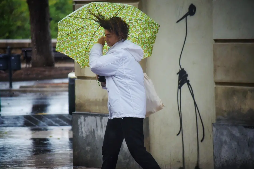 Una mujer camina por la calle sujetando su par&aacute;guas, movido por el viento, durante el temporal de gota fr&iacute;a que afecta a la zona de Levante, en Valencia (Espa&ntilde;a) a 11 de septiembre de 2019.