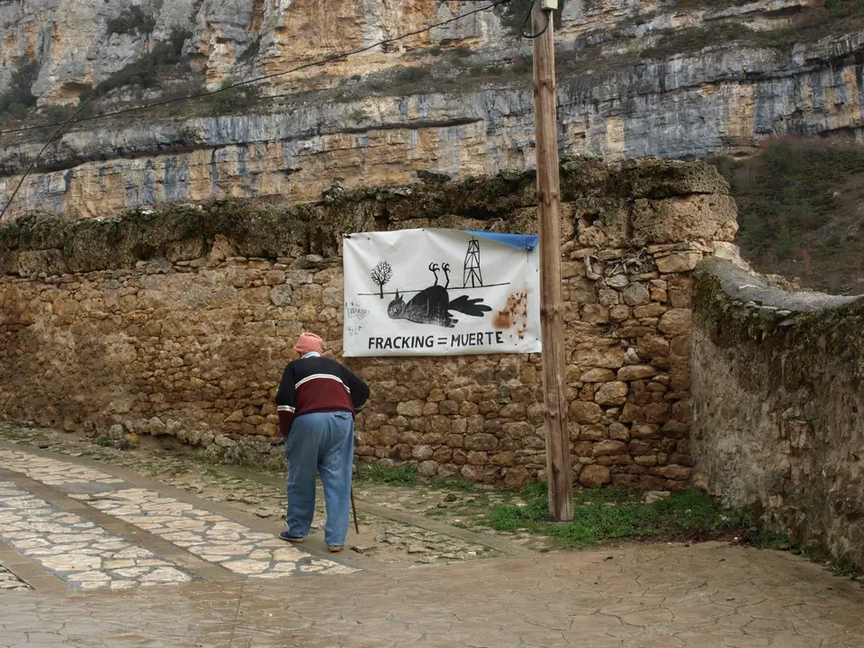 Hombre camina junto a cartel contra el fracking 