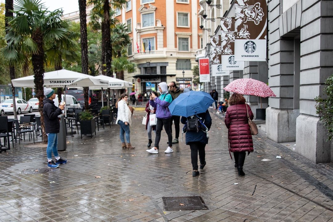 Varias personas pasean por la calle con un paraguas debido a la lluvia
