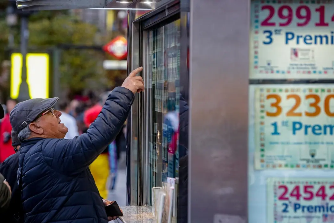Un hombre se&ntilde;ala el d&eacute;cimo de Loter&iacute;a de Navidad que quiere comprar en una Administraci&oacute;n en la plaza de Puerta del Sol, en Madrid (Espa&ntilde;a), a 18 de noviembre de 2019.