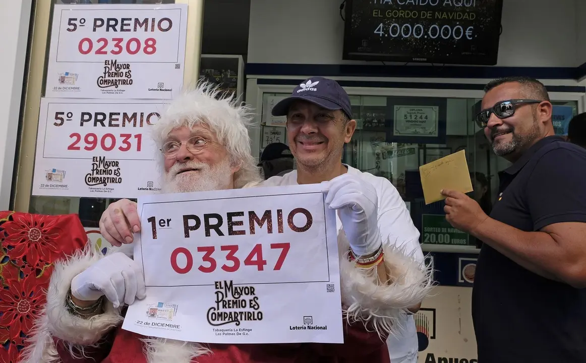 El propietario (con gorra) de la administraci&oacute;n de Loteria La Esfinge, de calle Ripoche n1 de Las Palmas de Gran Canaria, celebra, con algunos de los agraciados, que ha repartido parte del Gordo y el quinto premio del Sorteo de Loter&iacute;a Nacional.  