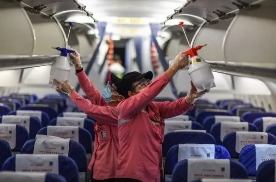 Empleados desinfectan la cabina de un avi&oacute;n despu&eacute;s de su llegada al Aeropuerto Internacional de Haikou Meilan, provincia de Hainan, en el sur de China.