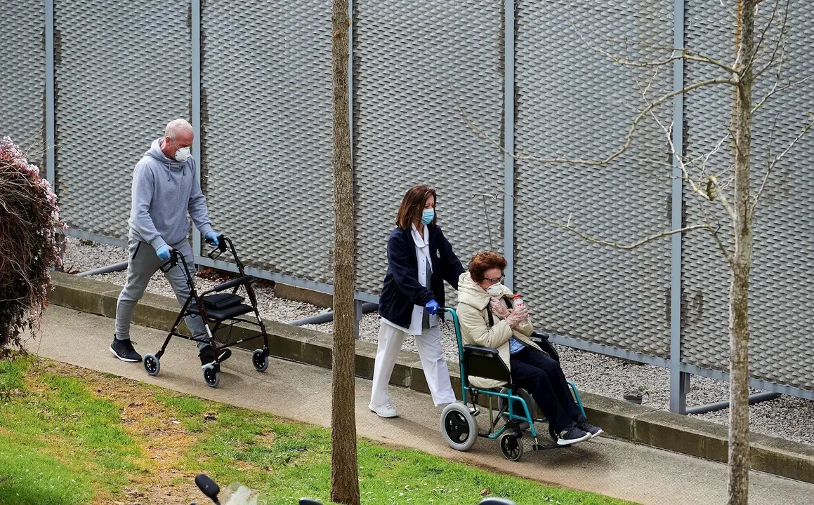 Una profesional sanitaria pasea con pacientes del Hospital Universitario Marqu&eacute;s de Valdecilla