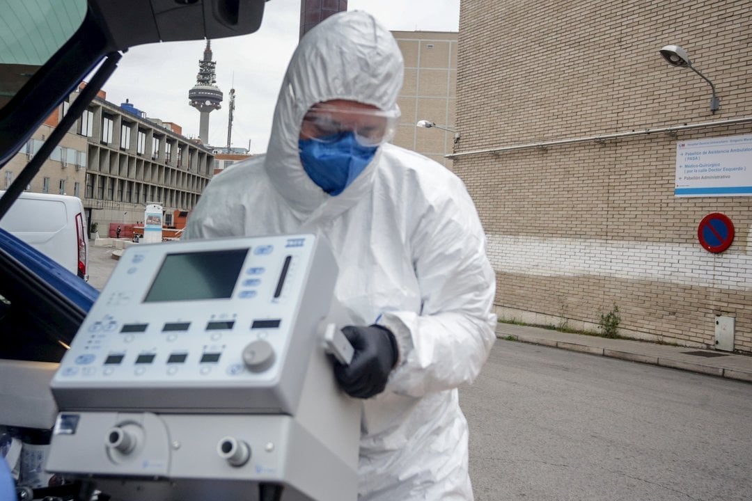 Un técnico protegido con un traje, guantes y mascarilla en el Hospital Gregorio Marañón, saca un respirador del maletero de su coche antes de montarlo en el Hospital, elemento imprescindible para muchos pacientes enfermos de coronavirus, en Madrid