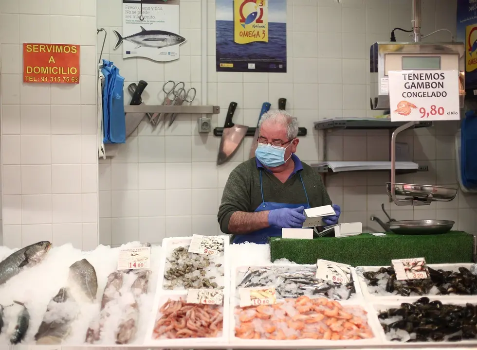 Un trabajador del Mercado municipal Barcel&oacute; ordena los productos alimenticios en su puesto de trabajo en plena crisis del coronavirus.