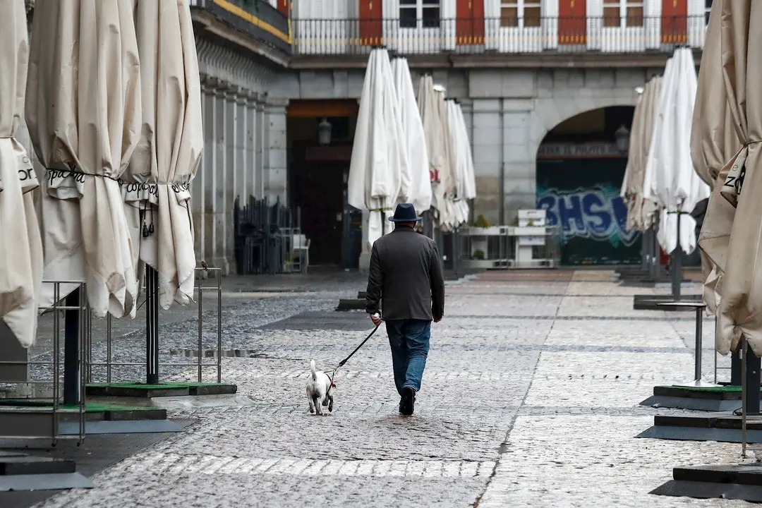 Un hombre pasea a su perro por la vac&rsquo;a Plaza Mayor de Madrid durante el sexto d&rsquo;a del estado de alarma por coronavirus, en Madrid (Espa&ndash;a) a 21 de marzo de 2020.