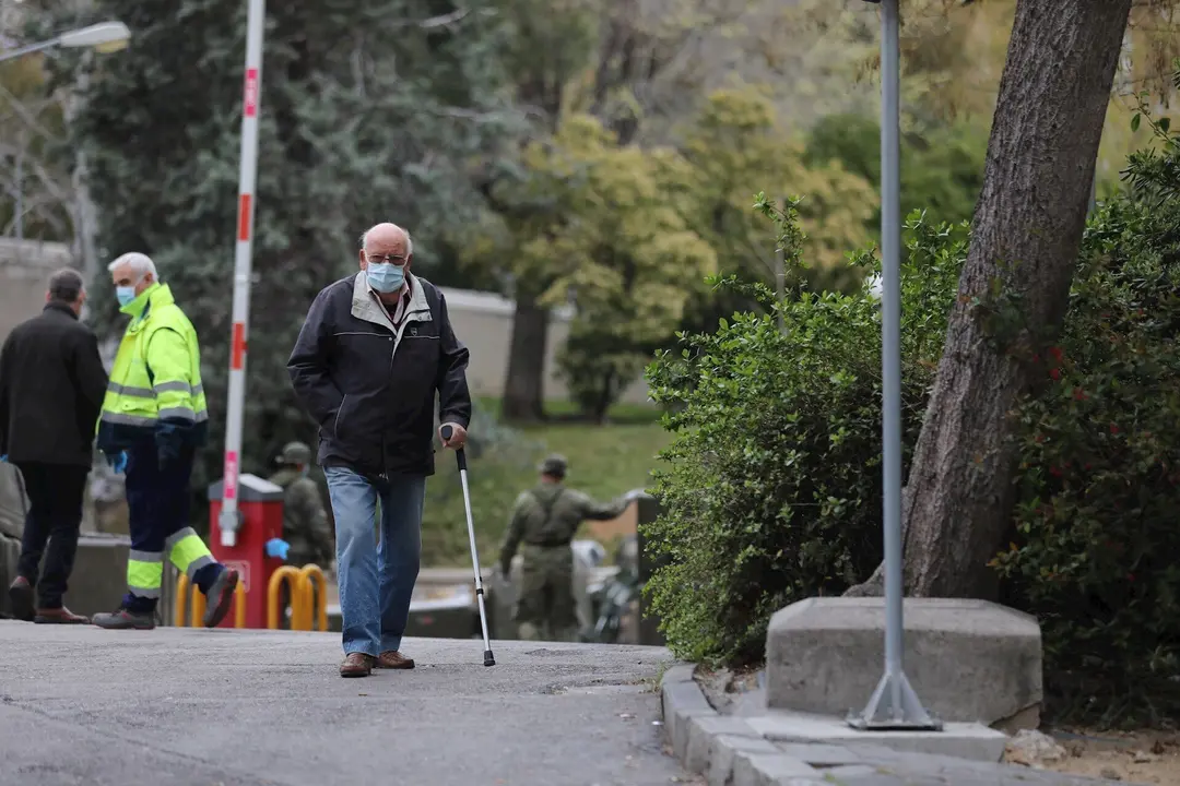 Un hombre con muleta y mascarilla pasa junto al &aacute;rea donde soldados del Mando de Ingenieros de Salamanca del Ej&eacute;rcito de Tierra, una unidad de 34 militares, instalan un hospital provisional de entre 60 y 70 camas en el Hospital Gregorio Mara&ntilde;&oacute;n