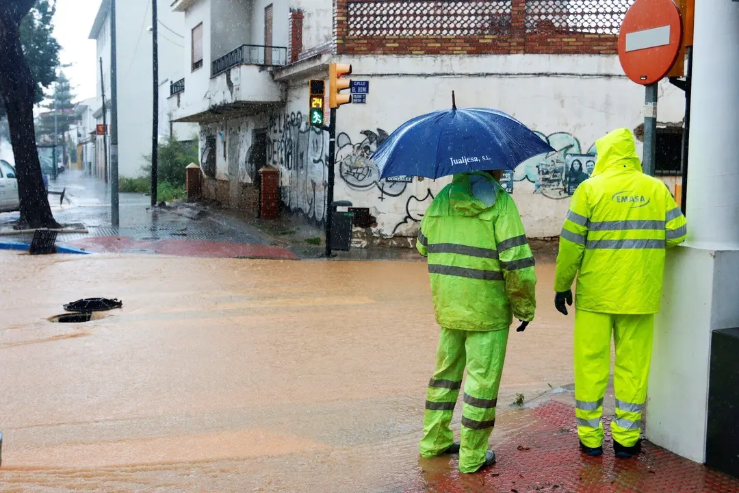 Operarios de los servicios operativos ayudan a retirar el exceso de agua acumulada en la barriada de Campanillas tras el desbordamiento del r&iacute;o  a causa de las fuertes lluvias ca&iacute;da la pasada madrugada. M&aacute;laga a 31 de marzo del 2020