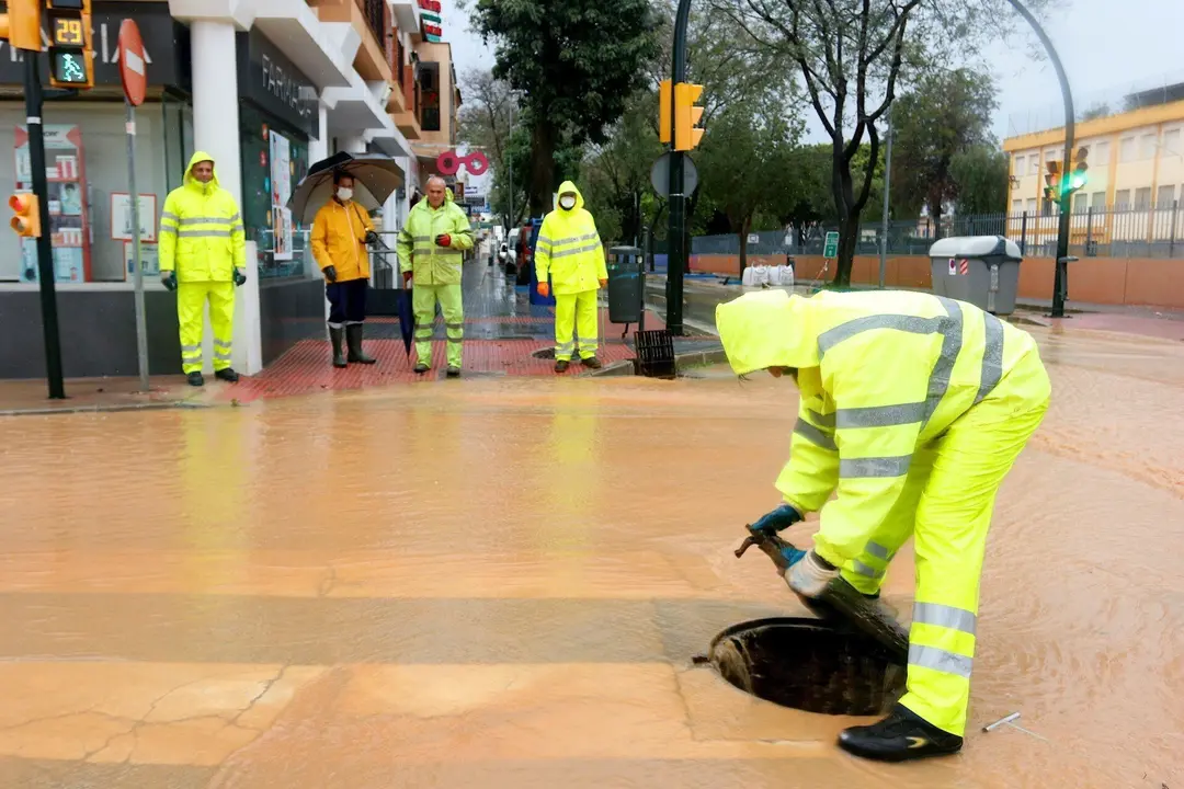Operarios de los servicios operativos ayudan a retirar el exceso de agua acumulada en la barriada de Campanillas tras el desbordamiento del r&iacute;o  a causa de las fuertes lluvias ca&iacute;da la pasada madrugada. M&aacute;laga a 31 de marzo del 2020