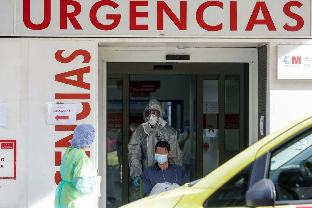 Un sanitario empuja una silla de ruedas con un enfermo leve de Covid-19 para su posterior traslado desde el Hospital de La Princesa al hospital de campa&ntilde;a en IFEMA 