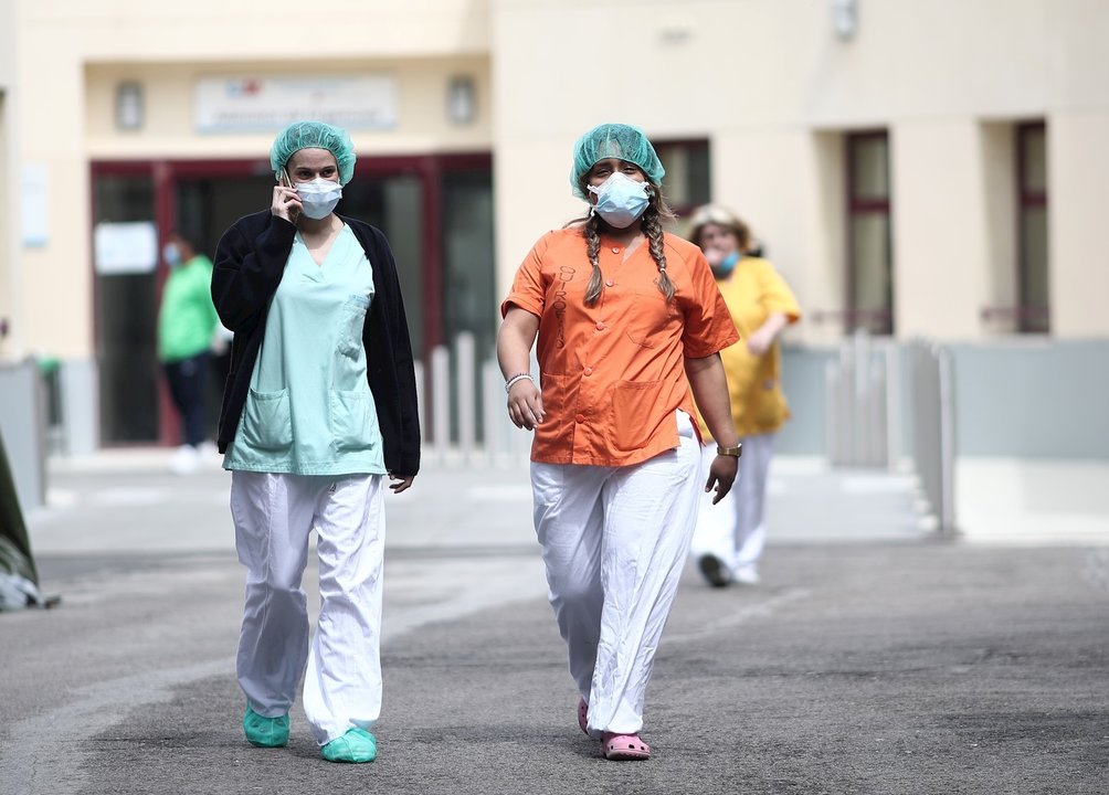 Dos sanitarias protegidas con mascarilla y gorro caminan cerca del Hospital de campaña en las inmediaciones de las Urgencias del Gregorio Marañón para la lucha contra el coronavirus, en Madrid (España) a 6 de abril de 2020.