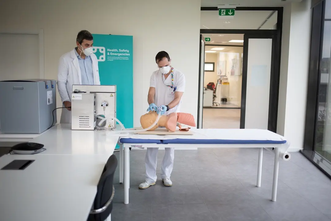 Dos operarios cl&iacute;nicos del proyecto de respiradores de SEAT muestran el funcionamiento de un respirador que han fabricado para los contagiados por coronavirus en un maniqu&iacute; de simulaci&oacute;n m&eacute;dica en las instalaciones de SEAT de Martorell
