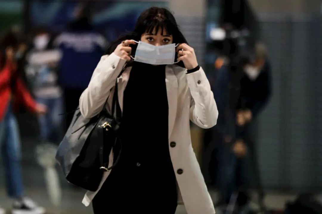 Una pasajera se coloca la mascarilla que previamente le han proporcionado Agentes de la Polic&iacute;a Municipal de Madrid en el intercambiador de la estaci&oacute;n Puerta de Atocha, en Madrid (Espa&ntilde;a), a 13 de abril de 2020.