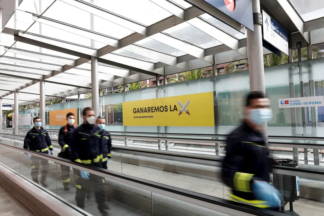 Bomberos de la Comunidad de Madrid protegidos con mascarilla caminan por las inmediaciones del hospital de campa&ntilde;a montado en IFEMA para contagios con coronavirus. En Madrid, (Espa&ntilde;a), a 11 de abril de 2020.