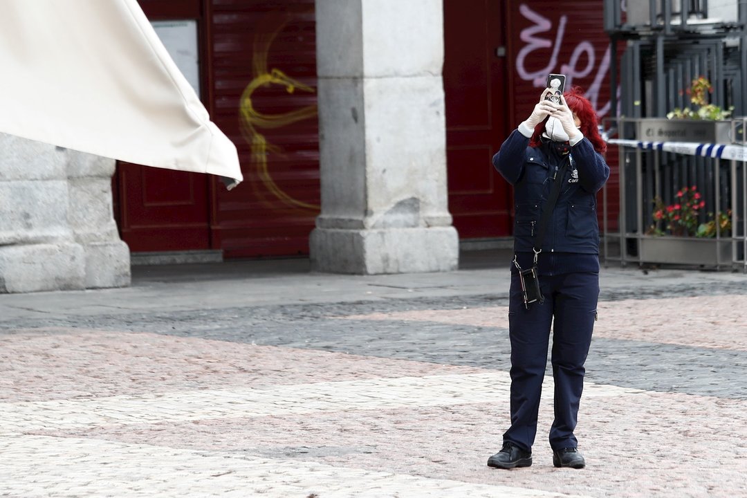 Una mujer hace una foto con su móvil en la Plaza Mayor de Madrid durante el primer día de la cuarta semana de estado de alarma decretado por el Gobierno para combatir el coronavirus