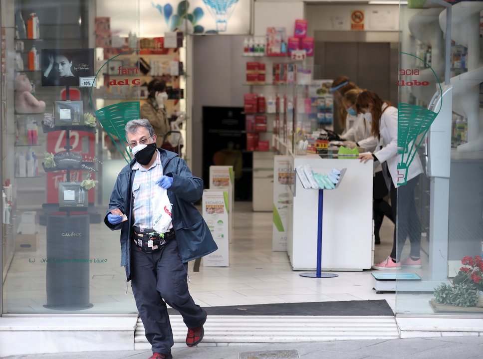 Un hombre protegido con mascarilla y guantes sale de una Farmacia. En Madrid (España) a 14 de abril de 2020.