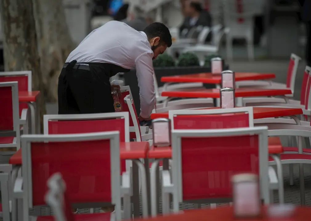 Un camarero limpia las mesas de un bar en Sevilla.