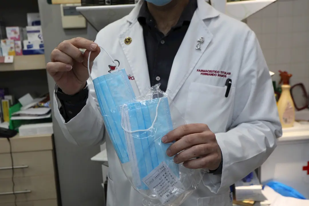 Un farmac&eacute;utico muestra una de las mascarillas que se venden en su farmacia durante el segundo mes de confinamiento, en Madrid (Espa&ntilde;a) a 20 de abril de 2020.