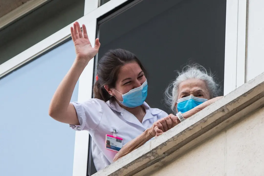 Una sanitaria ayuda a una paciente mayor a salir a la ventana para rendir homenaje a los sanitarios en el Hospital Fundaci&oacute;n Jimenez Diaz durante la pandemia de Covid-19 en Abril 20, 2020 in Madrid, Espa&ntilde;a