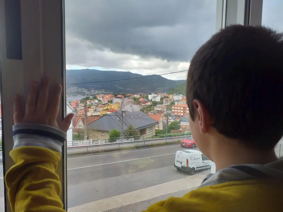 Un ni&ntilde;o observa la calle desde el interior de su casa, en pleno confinamiento por el estado de alarma decretado con motivo de la pandemia de coronavirus.