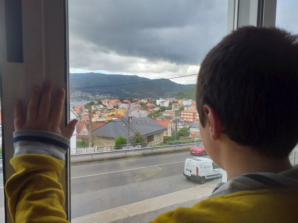 Un niño observa la calle desde el interior de su casa, en pleno confinamiento por el estado de alarma decretado con motivo de la pandemia de coronavirus.