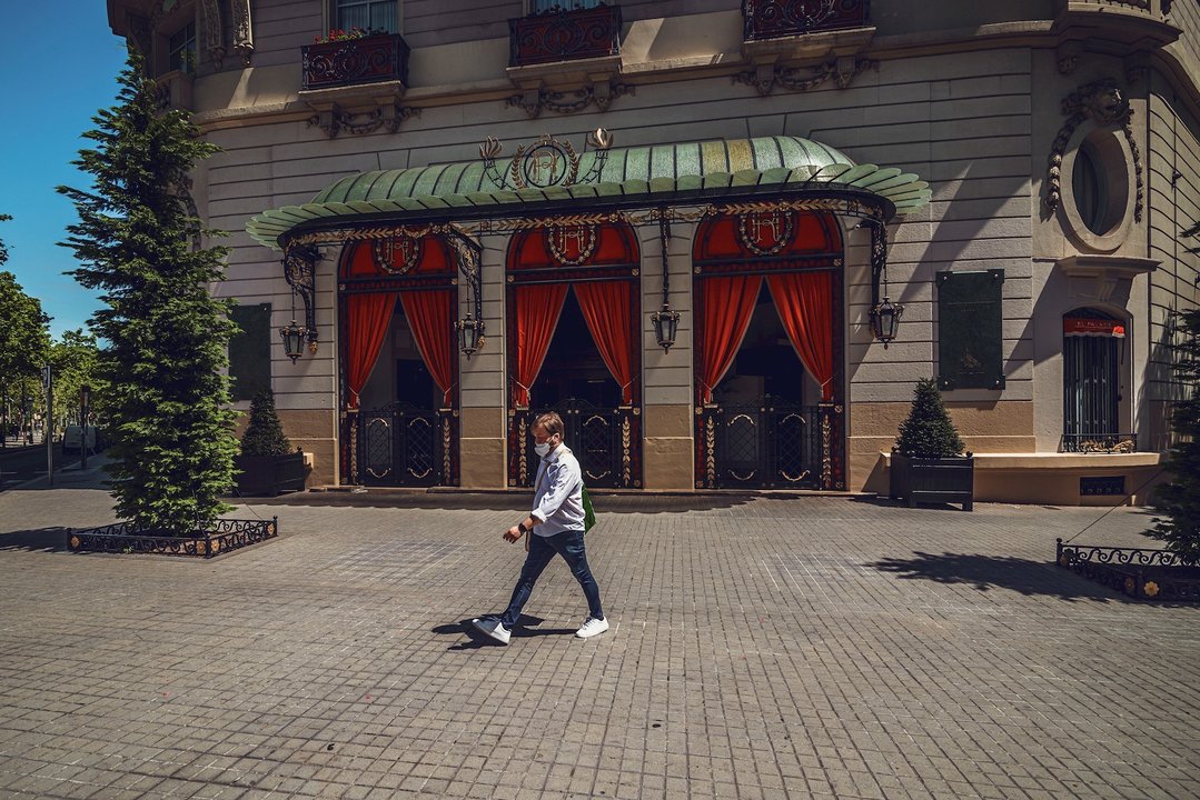 Un hombre camina por delante del hotel 'El Palace', en Barcelona, cerrado durante la crisis del coronavirus.