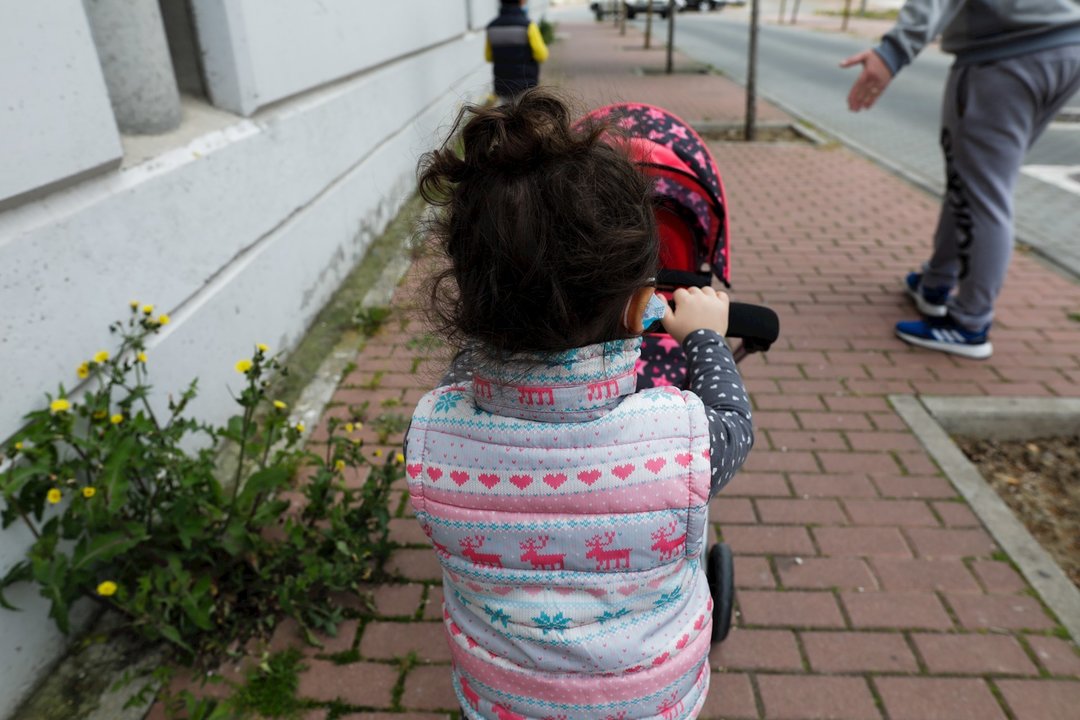 Una niña pasea por la calle empujando un carrito con un bebé de juguete junto a su padre y su hermano durante el segundo día de desconfinamiento de niños. En Madrid (España) a 27 de abril de 2020.