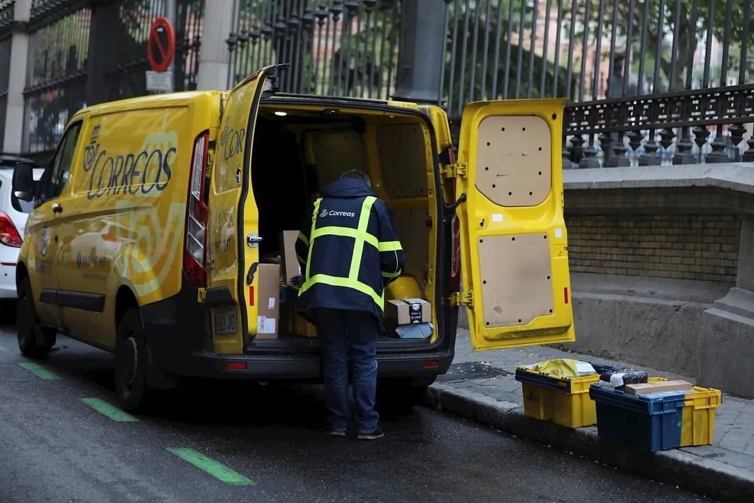 Un trabajador de Correos extrae de su furgoneta paquetes y cartas 