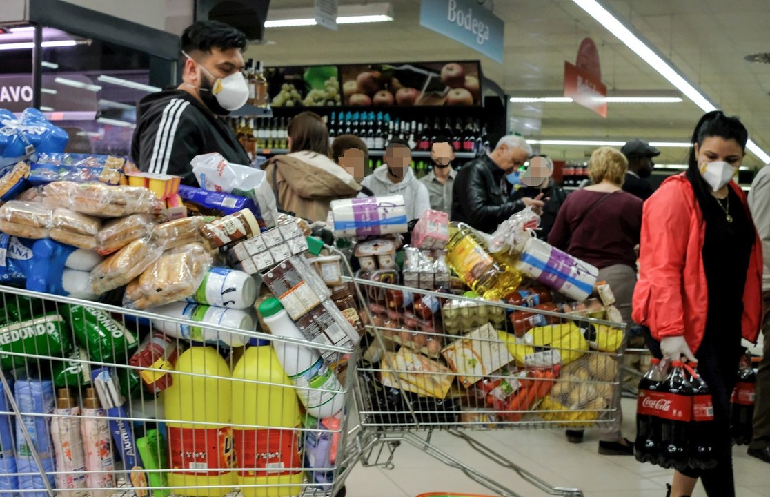 Decenas de personas cargadas con provisiones esperan para poder pagar en un supermercado 