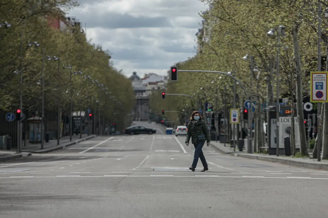 Una mujer pasea con mascarilla por el cruce entre la calle Serrano y la calle Ortega y Gasset, vac&iacute;o durante el estado de alarma, a 22 de marzo de 2020.