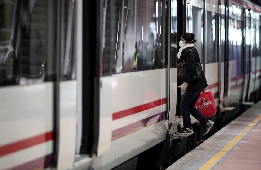 Viajeros entran en un tren de Cercan&iacute;as de Atocha portando mascarilla
