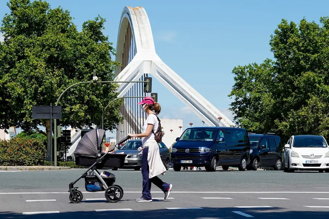 Una madre pasea a su hijo con el puente de la Barqueta detr&aacute;s,  un d&iacute;a despu&eacute;s de que el Gobierno de Espa&ntilde;a anunciara las medidas de desescalada por la pandemia del coronavirus, (Covid-19). En Sevilla (Andaluc&iacute;a, Espa&ntilde;a), a 29 de abril de 2020.