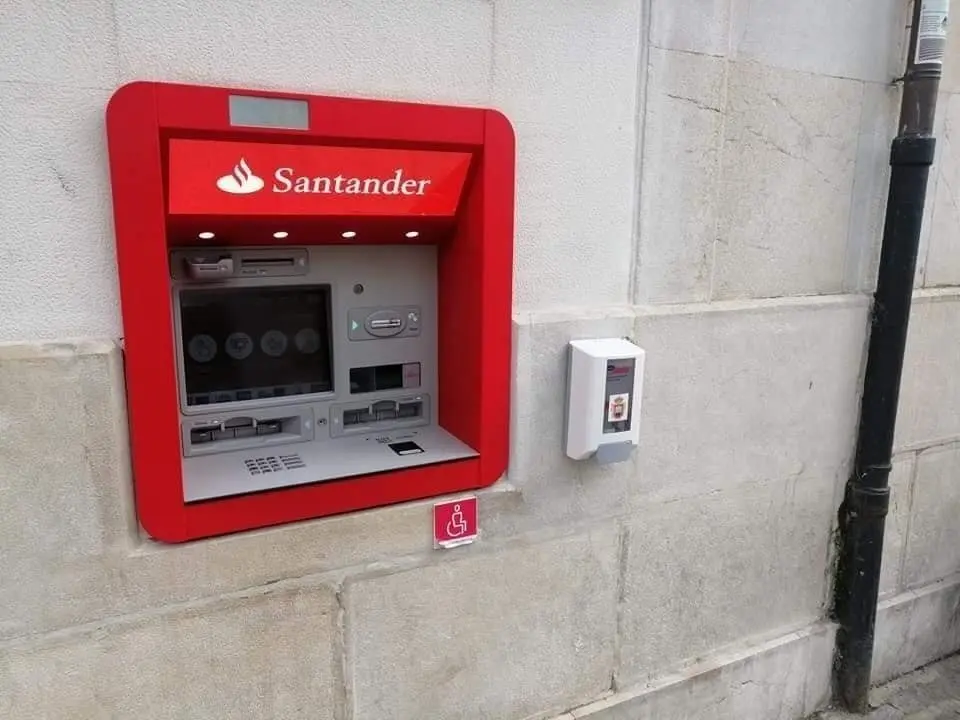 Dispensador de gel hidroalcoh&oacute;lico junto a un cajero autom&aacute;tico de una banco