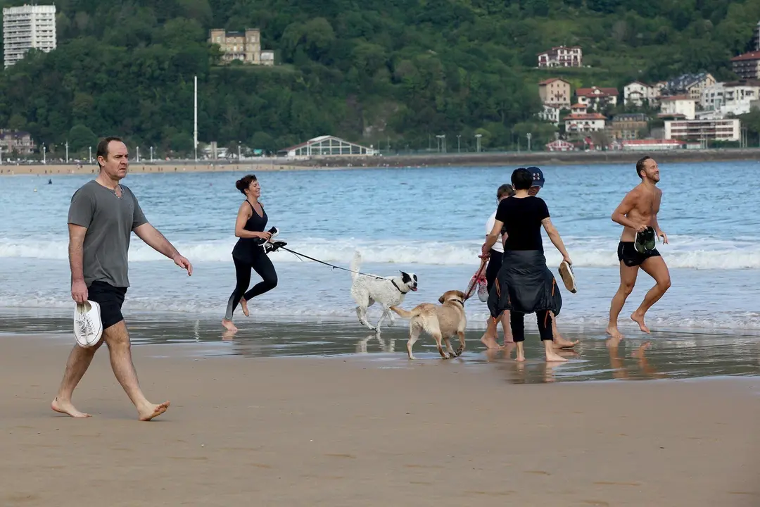 Varias persona caminan y corren con perros en la playa de La Concha en el d&iacute;a en que el Gobierno permite salir a hacer deporte de forma individual y pasear con otra persona con la que se conviva. En San Sebasti&aacute;n / Guip&uacute;zcoa (Espa&ntilde;a), a 2 de mayo de 2020.
