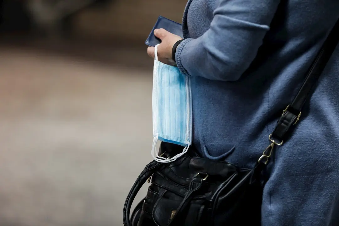 Una mujer porta una mascarilla en una mano en la estaci&oacute;n de metro de Sol durante la fase 0 de la desescalada del Gobierno en el inicio de la semana 8 del estado de alarma decretado por el coronavirus. En Madrid (Espa&ntilde;a), a 4 de mayo de 2020.