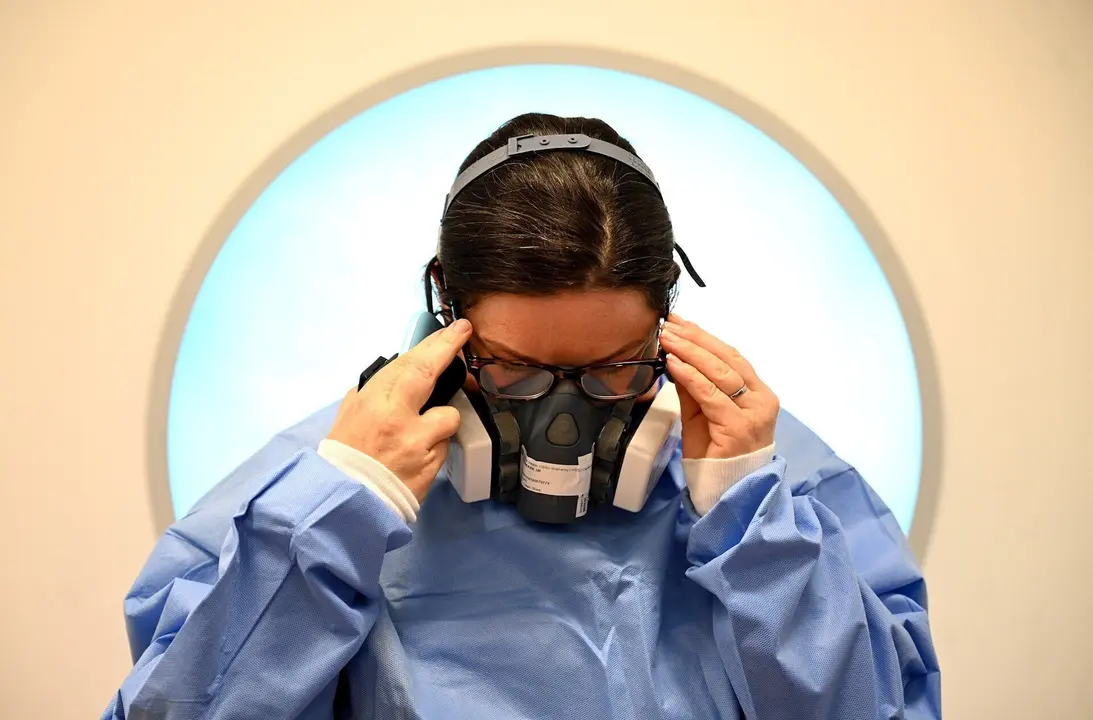 05 May 2020, England, Cambridge: A&nbsp;medic puts on Personal Protective Equipment (PPE) before working with Coronavirus patients in the intensive care unit at the Royal Papworth Hospital. Photo: Neil Hall/PA Wire/dpa