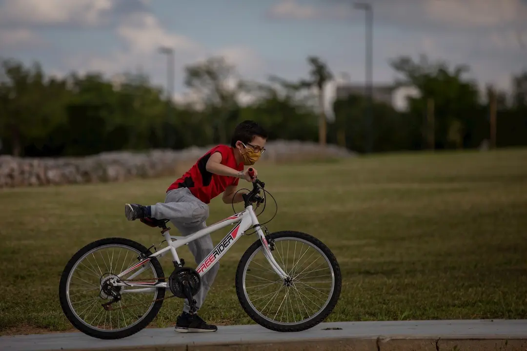 Un ni&ntilde;o protegido con mascarilla monta en bicicleta durante la crisis del coronavirus. En Sevilla (Andaluc&iacute;a, Espa&ntilde;a), a 28 de abril de 2020