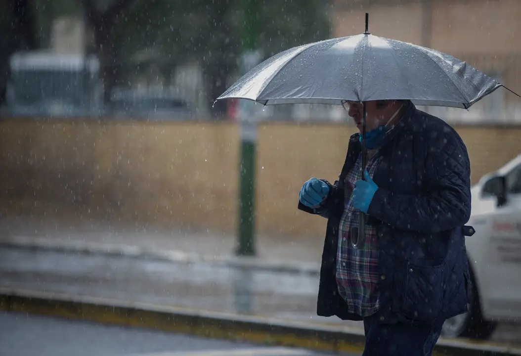 Un hombre camina bajo la lluvia protegido con un paraguas, durante la alerta amarilla. En el estado de alarma por la crisis del coronavirus, (Covid-19). En Sevilla, (Andaluc&iacute;a, Espa&ntilde;a), a 27 de abril de 2020.