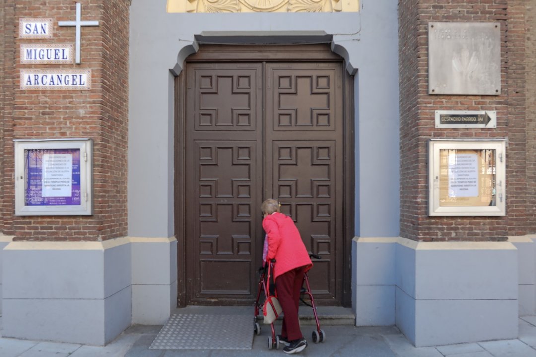 Una mujer intenta entrar en una iglesia con un cartel que indica que permanecerá