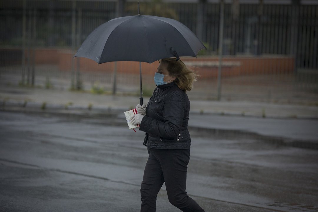 Una mujer bajo un paraguas en Sevilla durante el Estado de Alarma por la crisis del coronavirus, el dia 27 de abril de 2020
