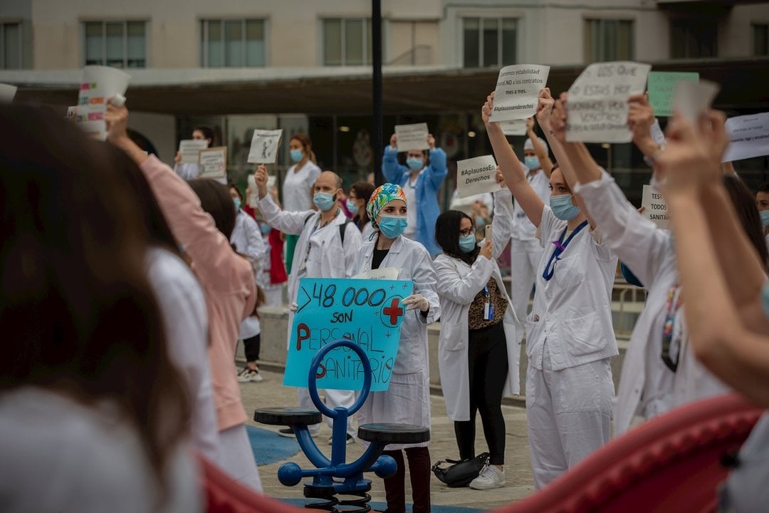 Decenas de miembros del personal sanitario protegidos con mascarilla sostienen carteles durante la concentración de sanitarios en el Día Internacional de la Enfermería a las puertas del Hospital Vall d'Hebron. En Barcelona, a 12 de mayo de 2020.