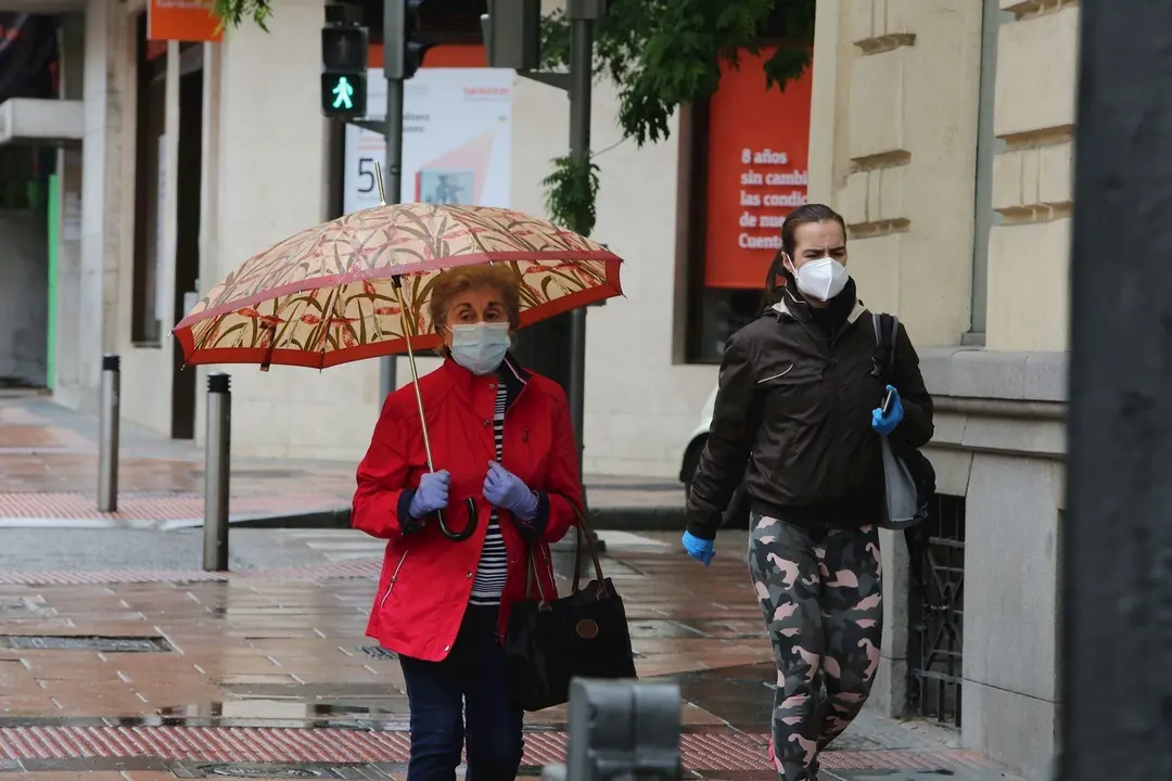 Dos mujeres pasean en la capital en un d&iacute;a de lluvia y bajada de temperaturas en toda Espa&ntilde;a, en que en gran parte de la Pen&iacute;nsula y Baleares se espera nubosidad, con chubascos y tormentas casi generalizados, que podr&aacute;n ser localmente fuertes o persistent