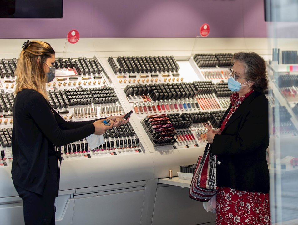 Una empleada de una tienda de cosmética atiende a una clienta
