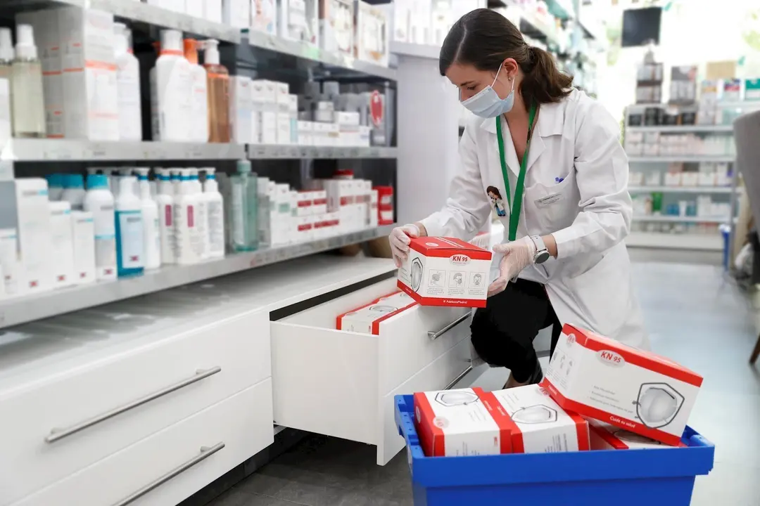 Una farmac&eacute;utica coloca cajas con mascarillas.