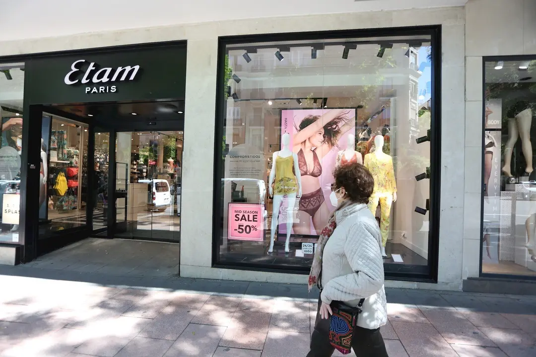 Una mujer pasa junto a una tienda Etam en la que se anuncian rebajas de hasta  el 50% el d&iacute;a en el que el Gobierno permite finalmente las rebajas desde hoy en toda Espa&ntilde;a siempre que no generen aglomeraciones, en Madrid (Espa&ntilde;a) a 18 de mayo de 2020.