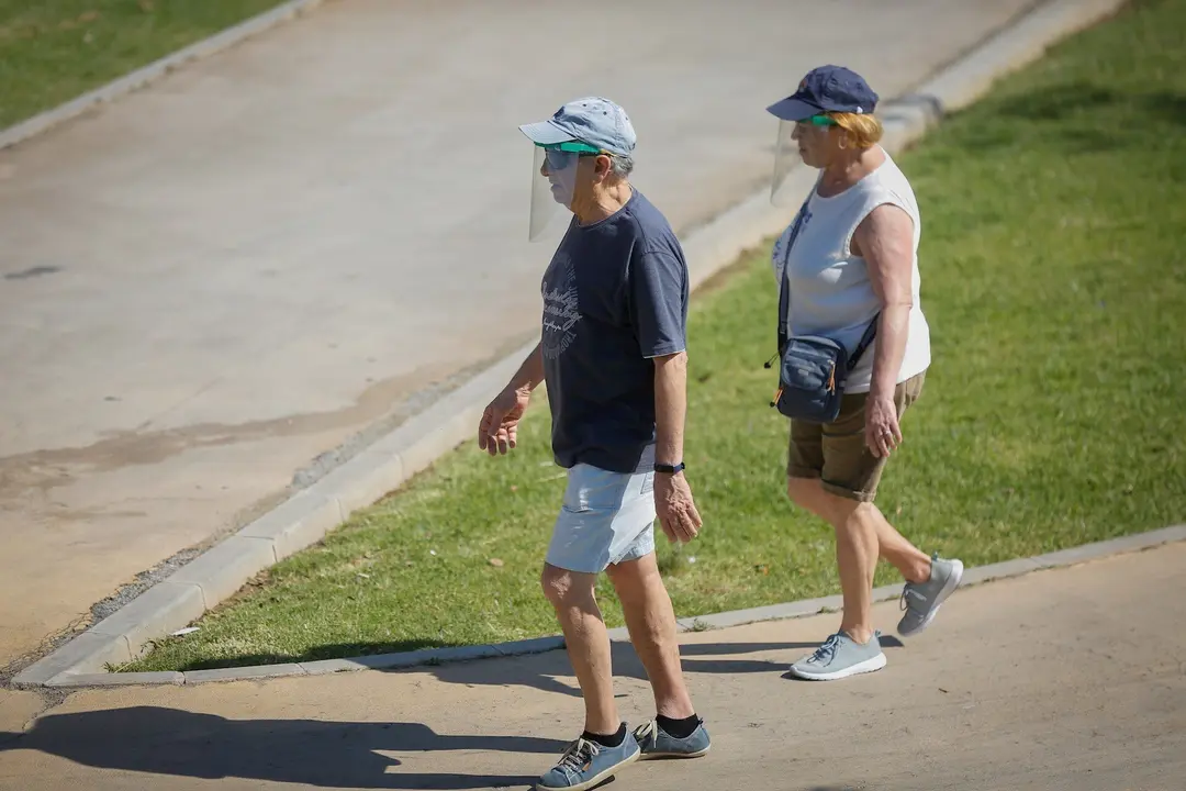 Dos personas con ropa veraniega y gorra pasean por el parque del Alamillo. En Sevilla (Andaluc&iacute;a, Espa&ntilde;a), a 21 de mayo de 2020.